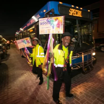 A man standing in front of a KCATA bus at Northeast Kansas City Chamber of Commerce Mardi Gras Event