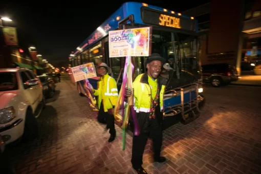 A man standing in front of a KCATA bus at Northeast Kansas City Chamber of Commerce Mardi Gras Event